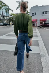 Jeans de tiro alto con pernera ancha y corte cropped. Presenta diseño de cinco bolsillos, cierre frontal con cremallera y botón, e incluye un cinturón a juego.