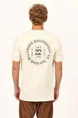 Remera Billabong de manga corta color crudo, con cuello redondo y pequeño estampado circular en el pecho.