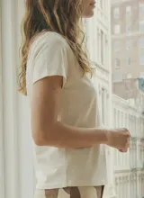 Remera negra de manga corta con escote en V adornado con un borde de encaje o puntilla.