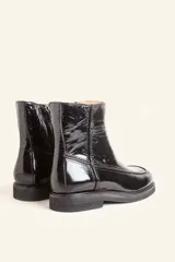 Bota corta de cuero vacuno con acabado charol brillante, diseño de punta cuadrada y suela de caucho con pequeña plataforma.