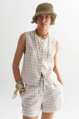 Top sin mangas color beige con estampado a cuadros blancos, con botones frontales.