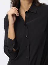 Camisa de manga larga en color negro, con cuello clásico y cierre frontal de botones. Presenta un corte entallado y puños con botones.