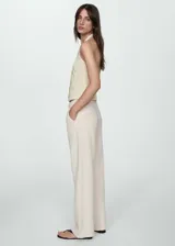 Pantalón de jean estilo vaquero en color beige, de tiro medio y diseño recto. Presenta cierre de cremallera con botón, trabillas en la cintura y detalle de pinzas frontales.