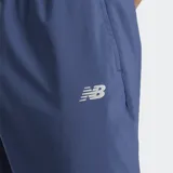 Pantalón deportivo New Balance modelo Sport Essentials Woven Jogger, color azul, confeccionado en poliéster reciclado. Presenta cintura elástica con cordón de ajuste, bolsillos laterales y puños ajustados en los tobillos.