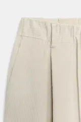 Pantalón de tiro medio confeccionado en tejido de pana, con diseño de pernera recta y holgada. Presenta pliegues frontales, cintura ajustable con lazada y cierre frontal con cremallera, botón y ganchos metálicos.