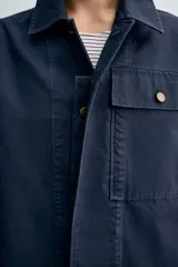 Sobrecamisa de corte regular confeccionada en tejido de algodón con estructura canvas, color negro. Presenta cuello solapa, manga larga con puño abotonado, un bolsillo frontal de plastrón y cierre frontal con botonadura oculta.