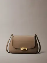 Cartera mediana de poliuretano color tostado, con diseño estructurado, solapa frontal, cierre de broche a presión metálico dorado con el logo de Calvin Klein y correa ajustable.