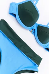 Bikini de dos piezas en combinación de colores negro y mostaza. El corpiño es de estilo triangular con base y breteles finos, mientras que la bombacha es de corte clásico con cintura alta en color negro.