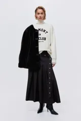 Buzo oversized color crema con cuello redondo acanalado. Presenta un estampado frontal en negro con el texto "VERMONT SKI CLUB Montpelier 1970" y un logo de montaña. Tiene hombros caídos y remates acanalados en puños y bajo.