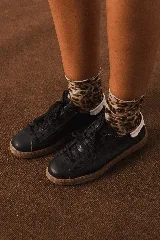 Championes de cuero negro con suela de goma color caramelo y detalle de talón en color blanco.