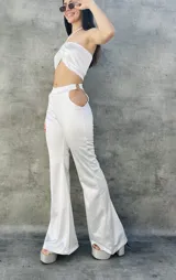 Pantalón blanco de tiro alto y corte acampanado, con aberturas circulares en los laterales de la cintura.