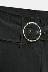 Pantalón capri de tiro medio confeccionado en tejido elástico, con cintura elástica y detalle de cinturón integrado con hebilla metálica circular. Presenta aberturas en el bajo.