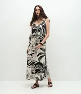 Pollera larga (midi) de corte evasé, con cintura elástica y lazo. Presenta un estampado grande en blanco y negro de motivos tropicales como hojas de palmera y flores.