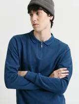 Remera de punto canalé francés azul, con cuello polo, manga larga y cierre metálico corto en el frente.