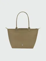 Bolso tote Longchamp modelo Le Pliage Green L, color marrón chocolate, confeccionado en lona de nylon reciclado con detalles en cuero ruso color marrón oscuro. Cuenta con cierre de cremallera y botón a presión, asas cortas para llevar al hombro y es plegable para facilitar su almacenamiento.