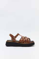 Sandalias marrones con plataforma negra y tiras anchas entrecruzadas con textura símil reptil. Ajuste con hebilla metálica lateral y suela de goma.