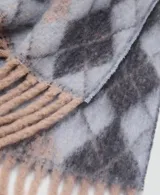 Bufanda de tejido de punto con diseño de rombos en tonos gris, celeste y beige, con terminaciones de flecos en los extremos.