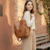 Mochila de eco cuero color suela, de diseño amplio con múltiples bolsillos externos con cierre y tiradores largos. Cuenta con asa superior y correas ajustables.