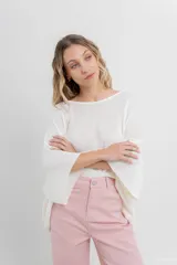 Sweater oversize de tejido liviano color blanco roto, con textura semi traslúcida, escote redondo y mangas amplias estilo murciélago.