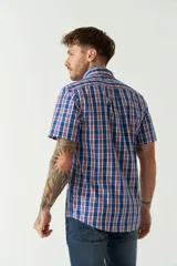 Camisa de manga corta con estampado de cuadros vichy en azul y blanco. Presenta cuello con botones, cierre frontal con botones y logo bordado en el pecho.