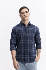 Camisa de manga larga confeccionada en viyela de algodón con diseño de cuadros en tonos azul y verde. Presenta cierre frontal con botones, cuello clásico y bolsillo en el pecho.