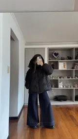 Campera puffer de corte holgado en color beige, con diseño acolchado, cuello alto y capucha desmontable. Cuenta con cierre frontal y botones a presión, además de puños elásticos.