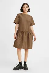 Vestido corto de corte amplio con diseño de cuadros en tonos marrones y negros. Presenta cuello redondo, mangas cortas y un detalle de cintura caída con falda fruncida.