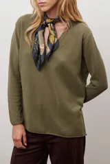 Sweater de tejido de punto color beige, con escote en V y mangas largas. Presenta un diseño básico y versátil de corte recto.