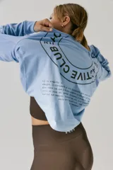 Remerón de manga larga color celeste, con cuello redondo y puños acanalados. Presenta una estampa circular en la espalda con el texto 'ACTIVE CLUB' y detalles de texto adicional en la parte inferior.