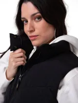 Chaleco acolchado tipo puffer color negro, con cierre frontal de cremallera, cuello alto protector y bolsillos laterales con cierre. Presenta un diseño técnico resistente al agua y al viento con forro interno estampado.