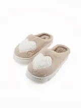 Pantuflas de peluche color beige con diseño de corazón blanco en la parte superior y suela de plataforma blanca.