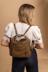 Cartera mochila versátil de cuero sintético con textura granulada, color negro. Cuenta con múltiples bolsillos frontales con cierre, correas ajustables que permiten su uso tanto como cartera de hombro o como mochila, y herrajes metálicos.