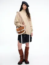 Sweater de tejido de punto color marrón, con cuello alto, corte amplio y tajos laterales en el ruedo. Presenta una costura vertical central en el frente y mangas largas con puños acanalados.