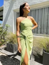 Vestido largo color naranja, con escote halter cruzado y falda tipo pareo con tajo lateral. Confeccionado en tela crepé con caída fluida.