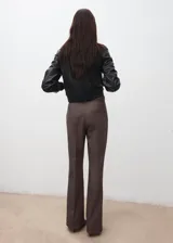Pantalón de vestir marrón, de corte recto y tiro alto, con bolsillos laterales y presillas para cinturón. Incluye un cinturón delgado del mismo tono con hebilla metálica.