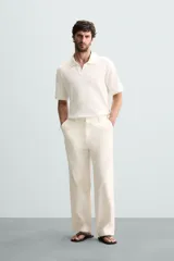 Polo de tejido canalé en color blanco, con cuello solapa y abertura frontal en V, de manga corta y corte regular.