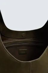 Bolso de hombro liso color verde militar, con compartimento principal con cierre de imán y un bolsillo interior con cremallera. Tiene un asa de hombro.