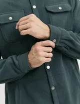 Sobrecamisa de micropolar color terracota, con cuello camisero, cierre frontal con botones a presión y dos bolsillos frontales con solapa y botón.