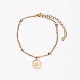 Pulsera dorada con cadena de eslabones y dije redondo con diseño de palmera.