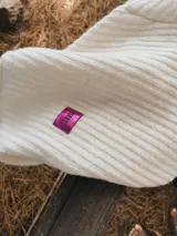 Saco tejido en lana color crudo, con corte recto, mangas largas y bolsillos frontales con apliques de estrellas de cuero en marrón, rosa y animal print.