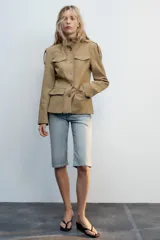 Cazadora de estilo militar en color tostado, con cuello subido, cierre frontal con botones y múltiples bolsillos con solapa en el pecho y la cintura. Cuenta con mangas largas con trabillas en los hombros.