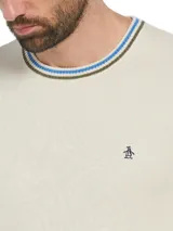 Sweater Original Penguin de hombre en color beige, confeccionado en 100% algodón. Cuenta con cuello redondo con detalles de líneas en verde y azul, puños y dobladillo acanalados, y el clásico logo bordado del pingüino en el pecho.
