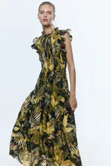 Vestido midi de mezcla de viscosa, con cuerpo fruncido, cuello de volados y sin mangas con volados en los hombros. Presenta costura fruncida en la cadera y falda amplia con vuelo. Estampado de hojas y flores tropicales en tonos verdes, amarillos y negros.
