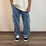 Pantalón de jean estilo cargo con corte baggy, color azul lavado. Presenta cuatro bolsillos laterales de gran tamaño con solapa y cierre de botones, diseño de pierna ancha y tiro medio.