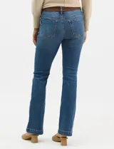 Jean de tiro alto con corte bootcut, color azul medio, con diseño de cinco bolsillos y costuras en contraste. Incluye un cinturón trenzado de cuero sintético con hebilla metálica.