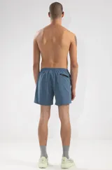 Short de baño azul con cintura elástica y cordón ajustable. Presenta bordados de sirenas en las piernas, bolsillos laterales y bolsillo trasero con cierre.
