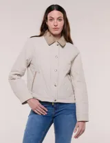Campera acolchada capitoneada, marca Michael Kors, de color beige con cuello camisero de gamuza en contraste. Cuenta con cierre frontal de botones a presión metálicos, bolsillos laterales inclinados con ribetes de gamuza y mangas largas.