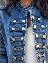 Chaqueta de denim estilo militar con cuello mao, cierre frontal con botones metálicos y detalles de trabillas horizontales. Presenta hombreras decorativas y diseño estructurado.