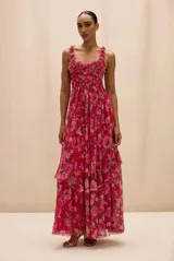 Vestido largo color fucsia con estampado floral, escote cuadrado y tirantes anchos adornados con detalles texturizados. Presenta un corpiño estructurado y una falda larga fluida con capas y vuelo.