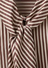 Blusa de manga larga con estampado de rayas verticales en tonos marrones y crema. Presenta un cuello alto con una corbata integrada del mismo tejido y cierre frontal de botones ocultos.